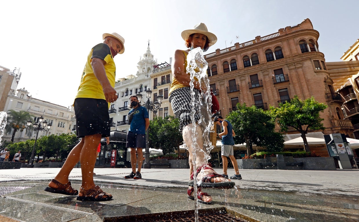 Dos turistas juegan con uno de los chorros de las fuentes de Las Tendillas en Córdoba