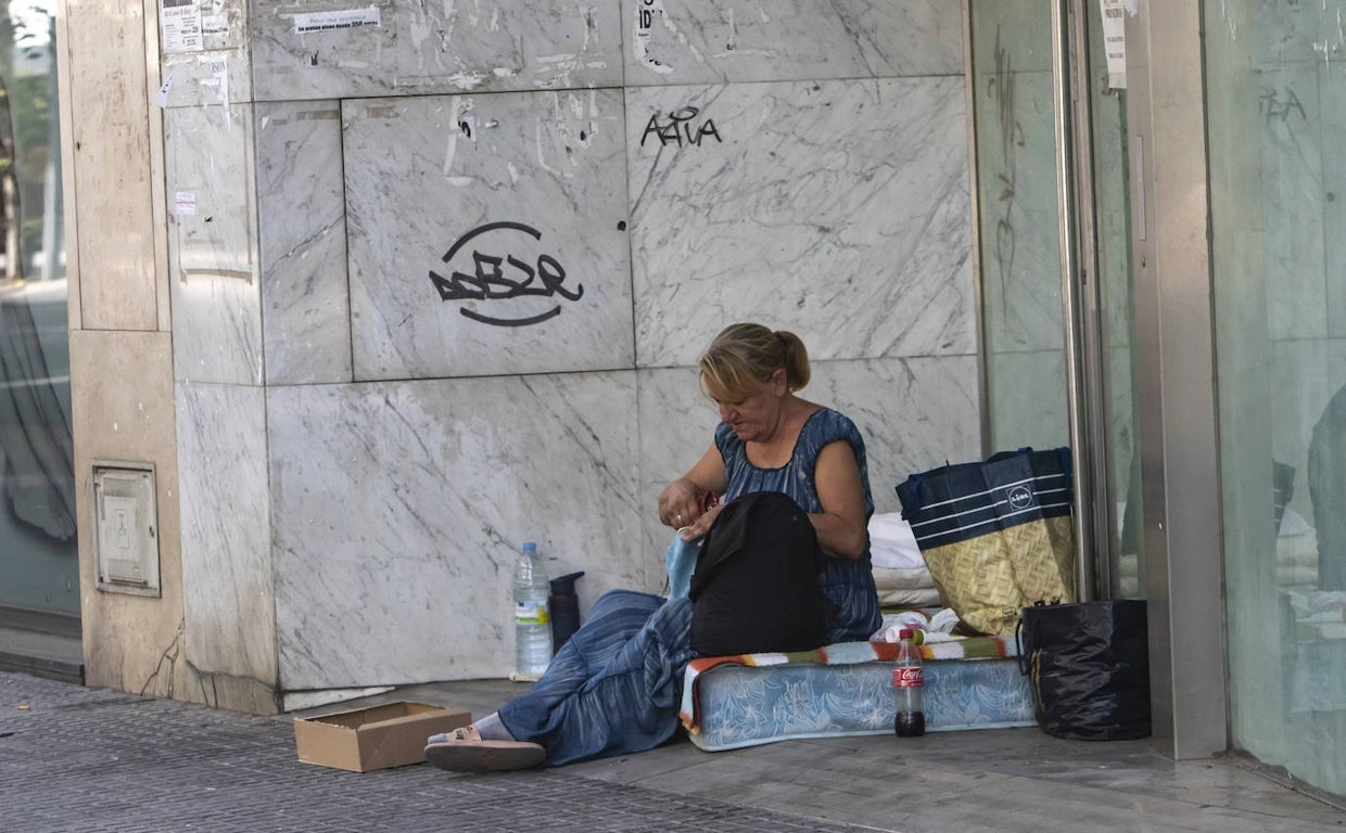 Una mujer descansa en un colchón en la calle