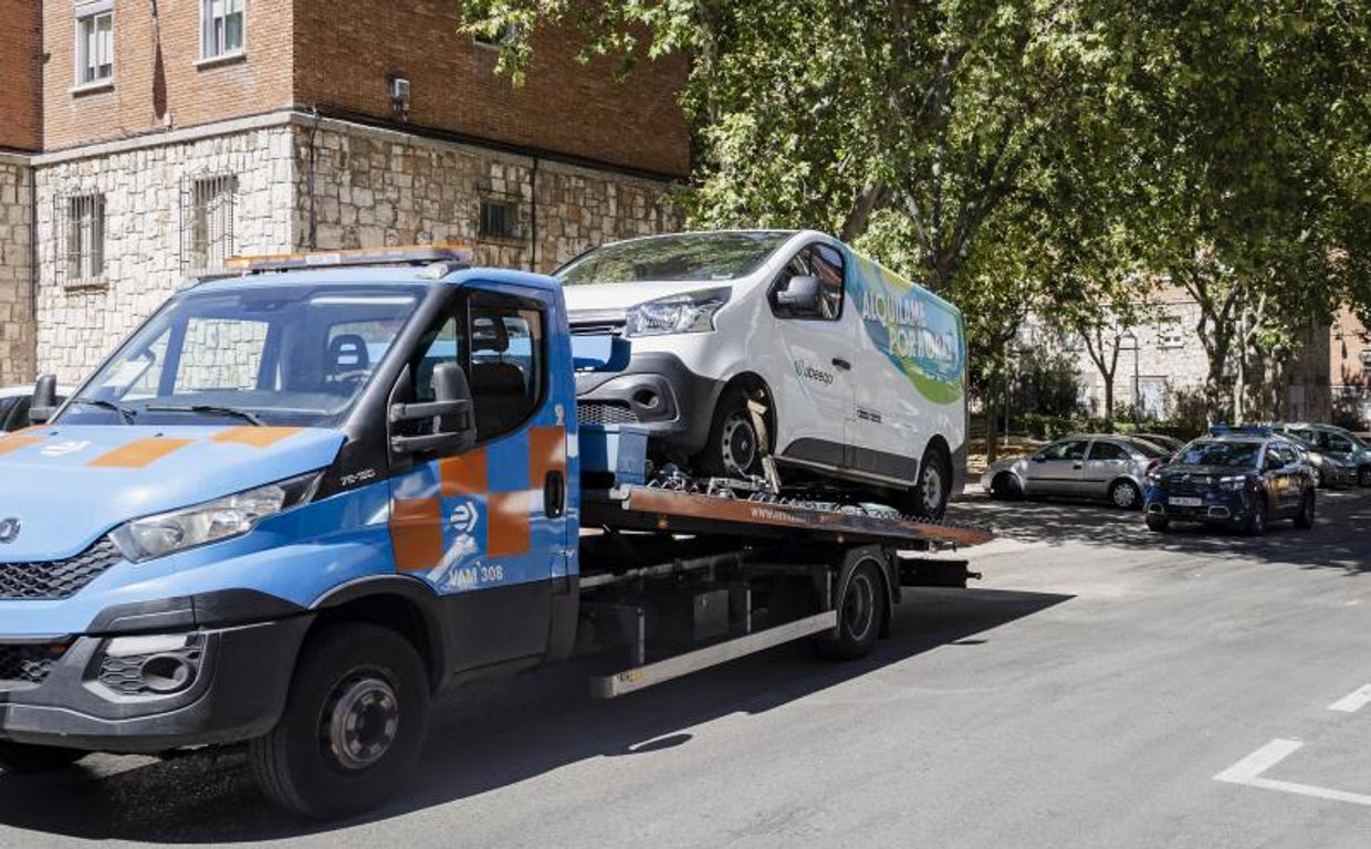 Una grúa municipal retira la furgoneta de alquiler, donde se desplomó el segundo fallecido