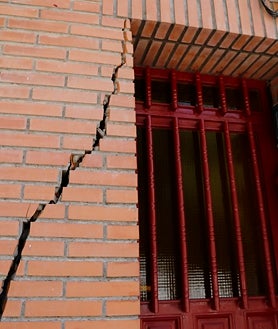Imagen secundaria 2 - El solar del edificio demolido, cubierto por cemento; pancartas pidiendo soluciones, y grietas en algunos de los edificios