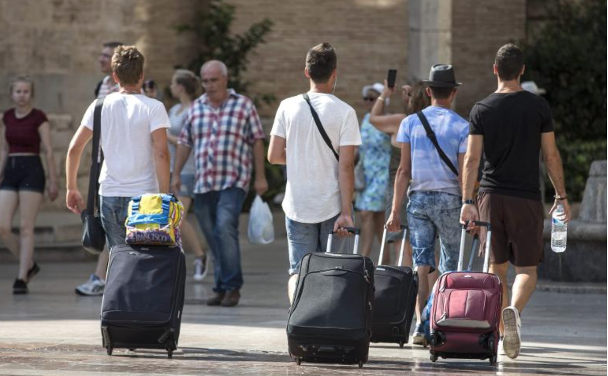 Grupo de turistas con sus maletas pasean por Valencia en foto de archivo