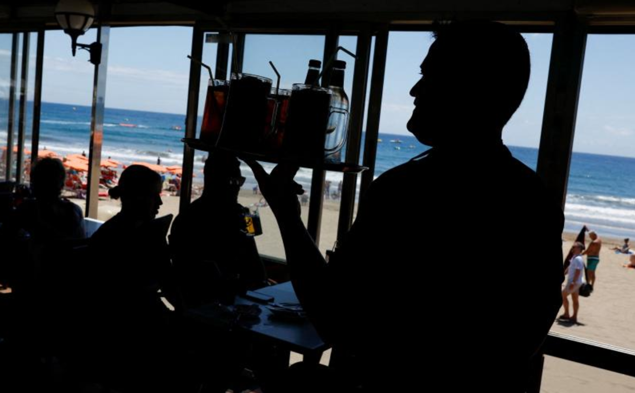Un camarero lleva una bandeja de bebidas en un local de Maspalomas
