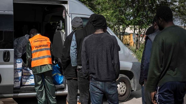 Algunos inmigrantes reciben comida de una ONG