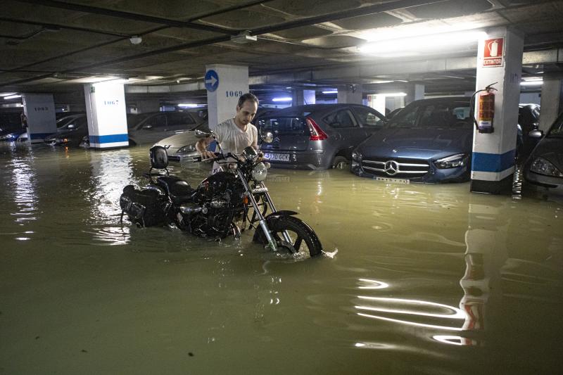 Un ciudadano trata de retirar su motocicleta en un garaje inundado