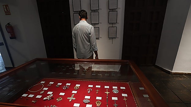 Broches y otros regalos a la Virgen, en la vitrina, y en la pared, las partituras