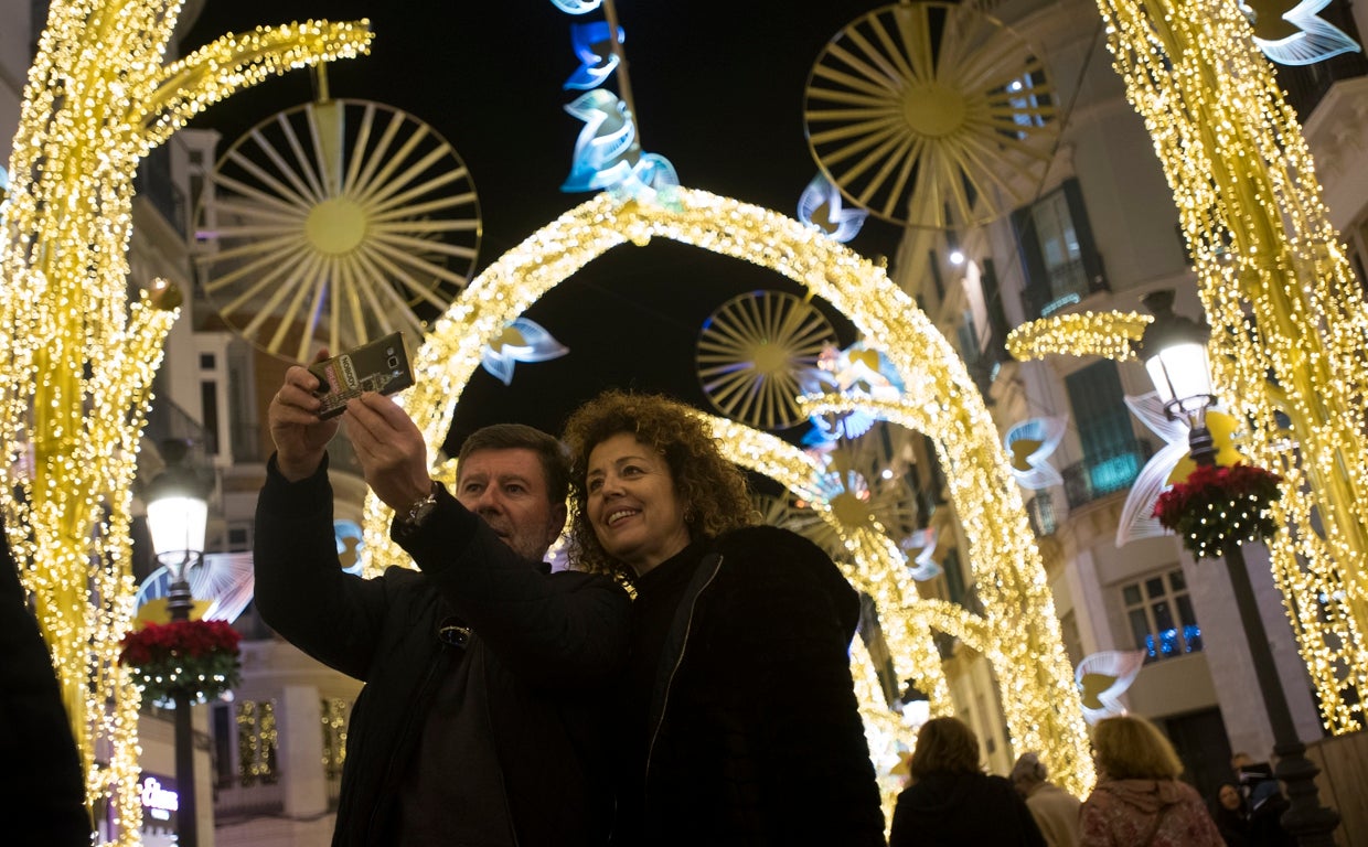 Una pareja se fotografía bajo el 'Bosque de la Navidad' de la calle Larios