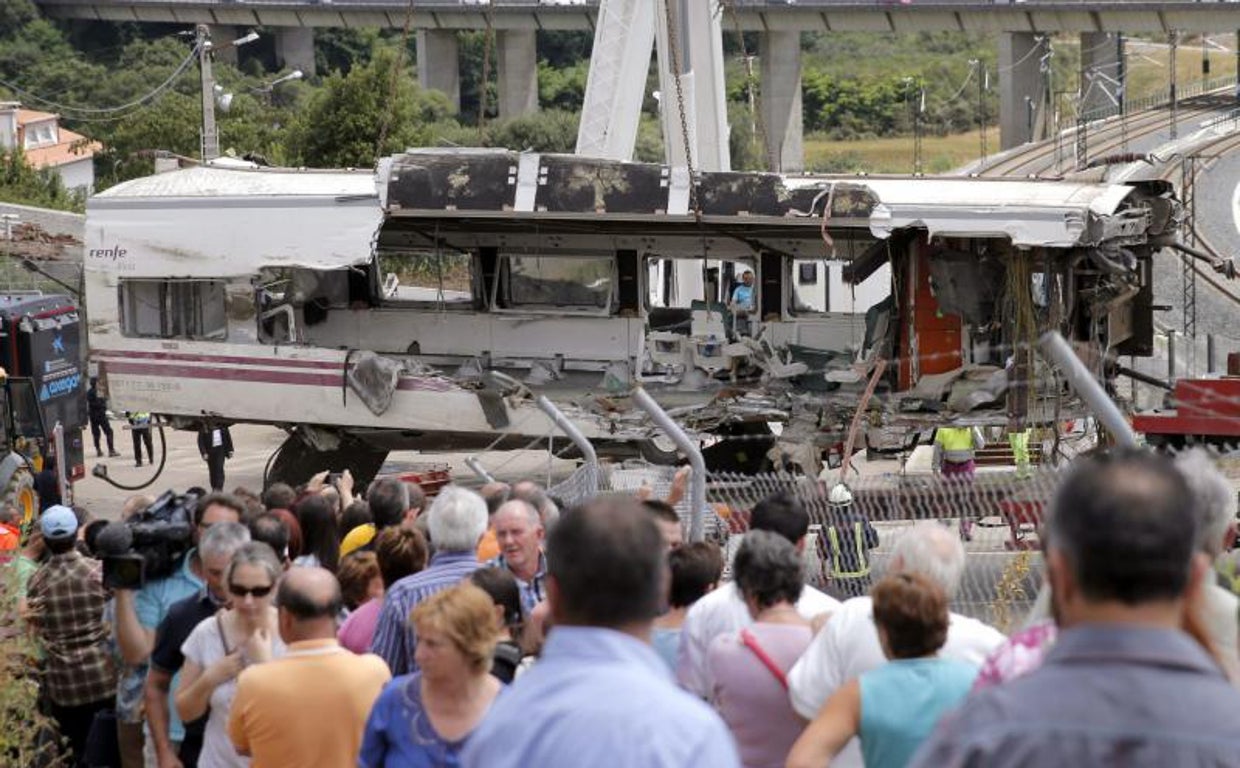 Un grupo de personas contempla la retirada de los vagones al día siguiente del accidente