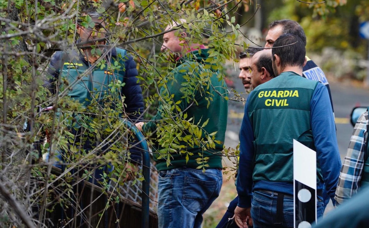 El detenido, con jersey verde, entre los investigadores durante el registro de ayer