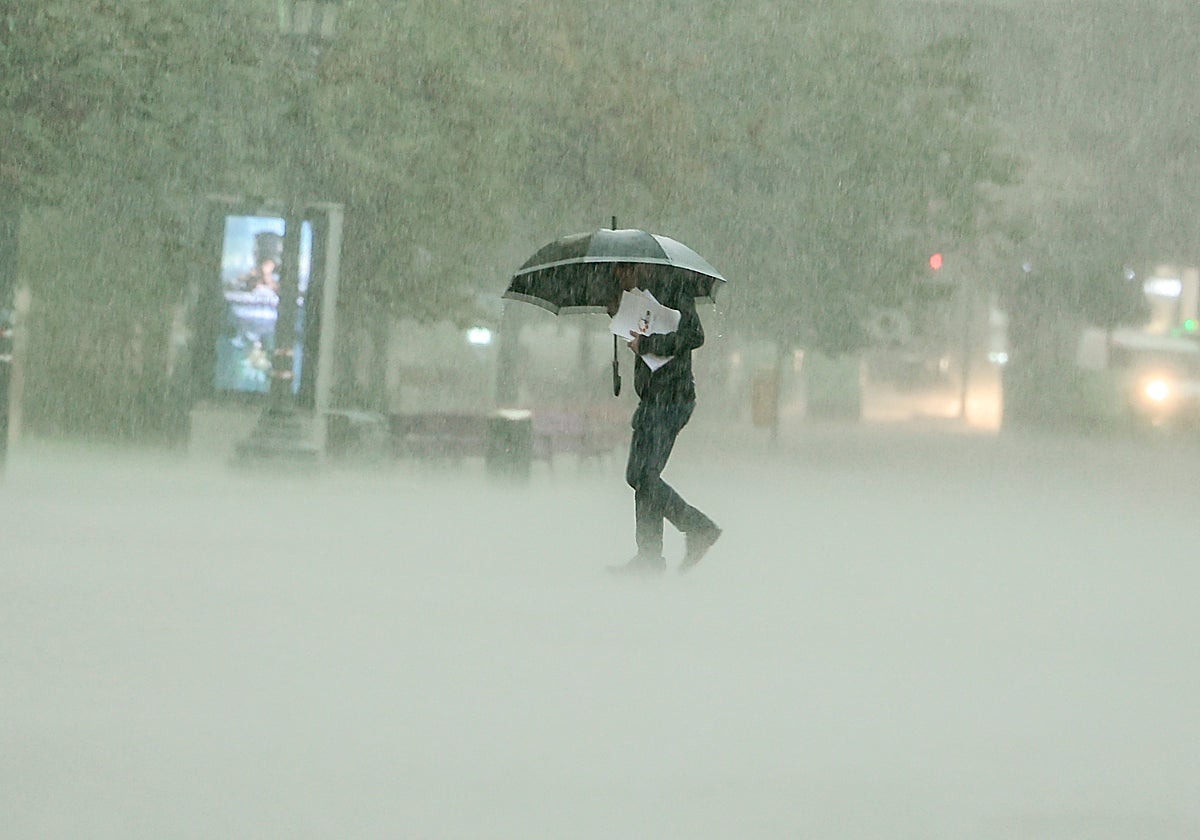 Un ciudadano se resguarda de la lluvia en Valencia