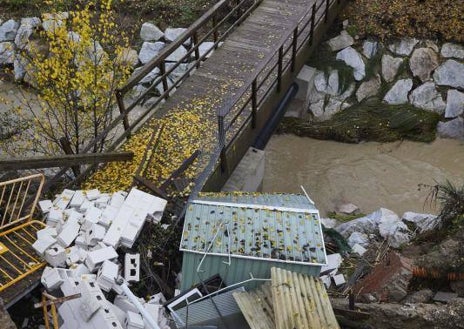 Imagen secundaria 1 - Los vecinos muestran cómo el río invade sus casas (imagen principal) con fuertes lluvias y deja destrozos a su paso, con casetas de jardín (segunda imagen) y muros de viviendas derribados. 