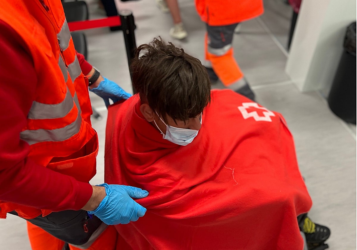Personal de Cruz Roja atendiendo al inmigrante en silla de ruedas llegado en patera a Benidorm este lunes.