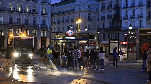 Los servicios de limpieza baldean la Puerta del Sol al amanecer
