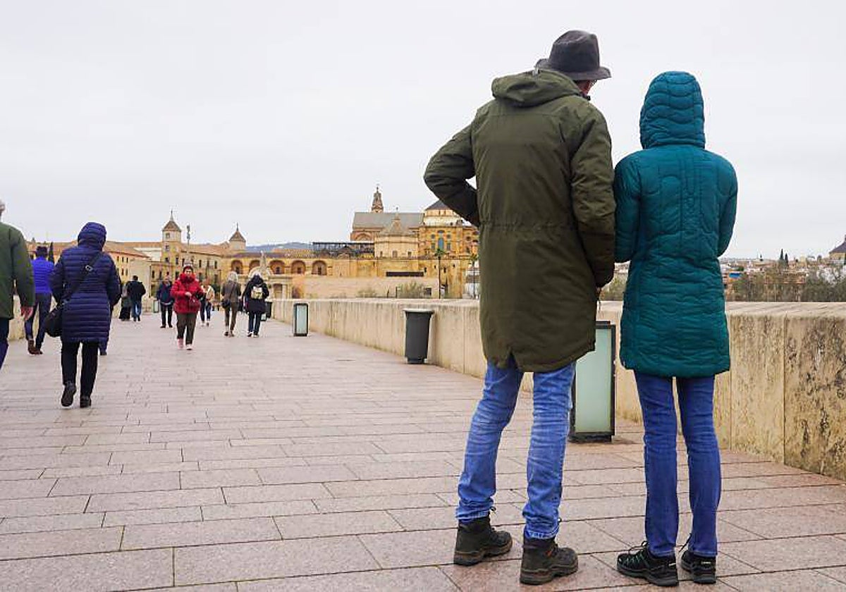 Una pareja se protege del frío este lunes en el Puente Romano de Córdoba
