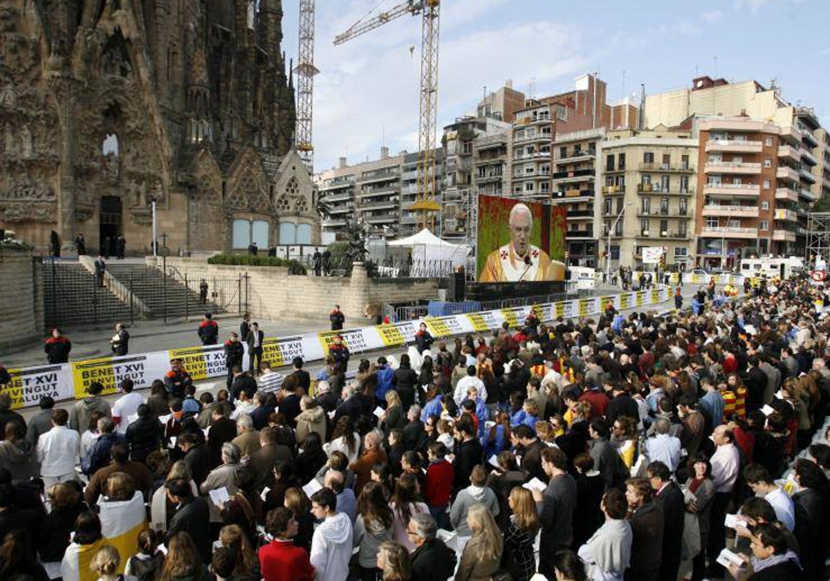 Una pantalla muestra a Benedicto XVI, en el exterior de la Sagrada Familia, el día que la consagró