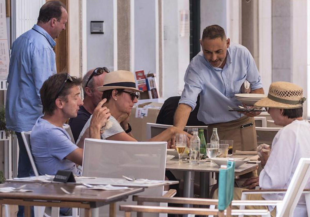 Un trabajador de hostelería atiende a unos clientes esta mañana en Menorca