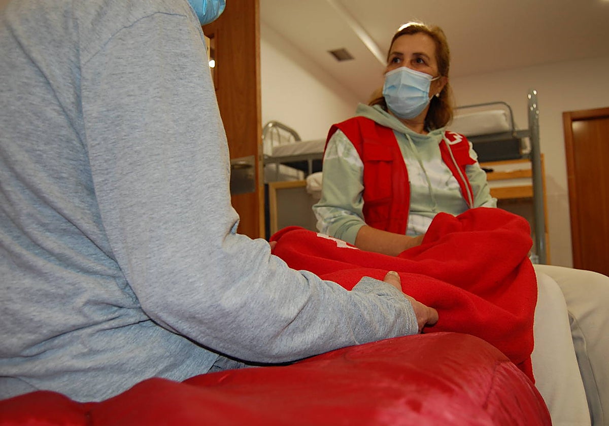 Una voluntaria de Cruz Roja charla con un hombre que se queda a dormir en uno de los albergues de Castilla y León