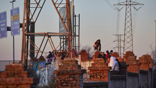 Los menores se sientan con las piernas colgando hacia el interior del perímetro ferroviario