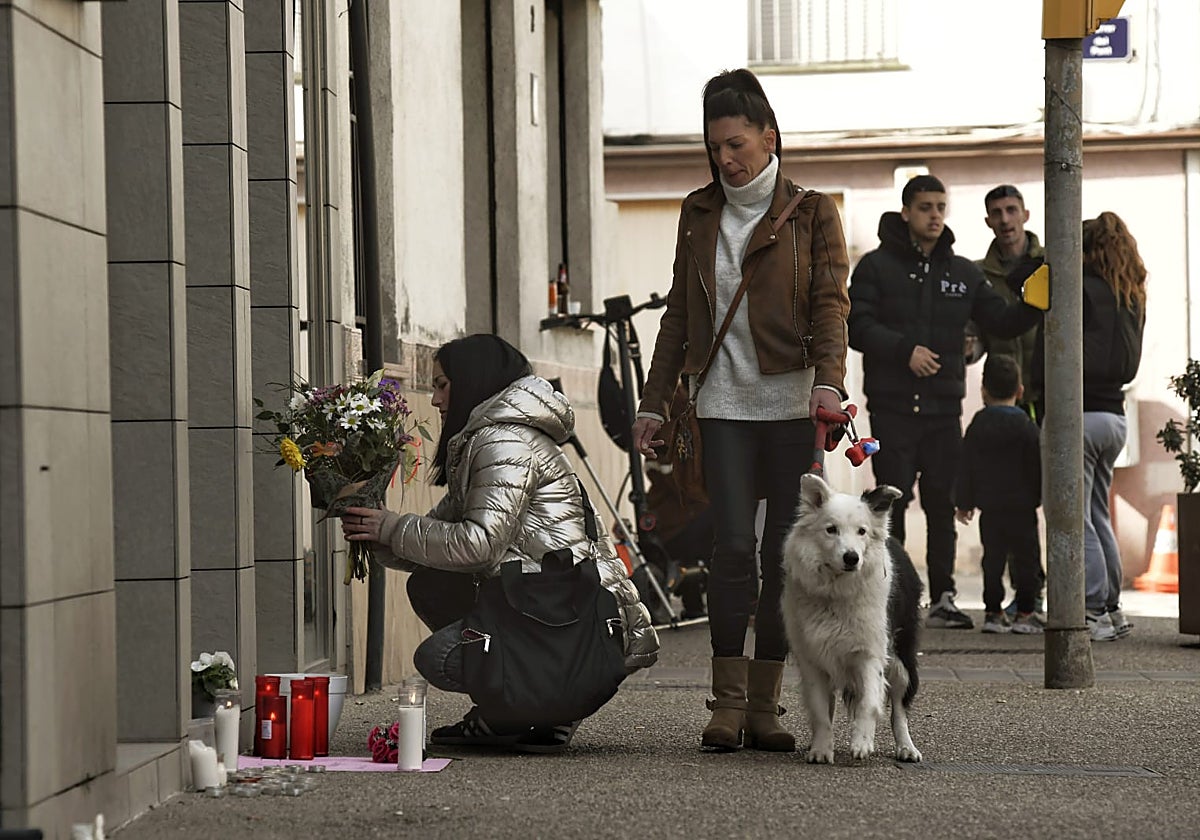 Una vecina deposita un ramo de flores frente a la puerta de la finca en que vivía la joven