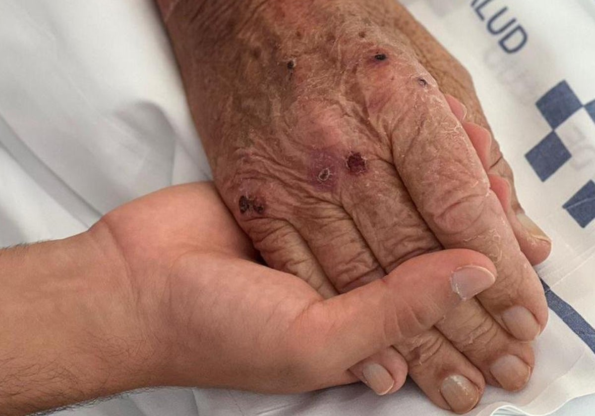 Una usuaria toma la mano de un mayor en foto de archivo