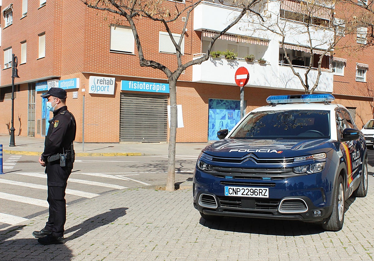 Un agente junto a un coche patrulla de la Policía Nacional.