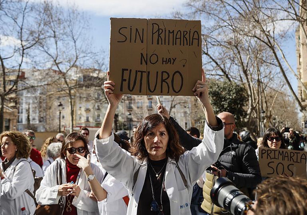 Una mujer con bata blanca sujeta una pancarta durante una protesta en la huelga de médicos en Valencia