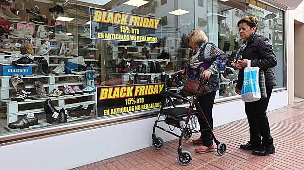 Dos mujeres miran el escaparate de un comercio en la Viñuela en el último 'black friday'
