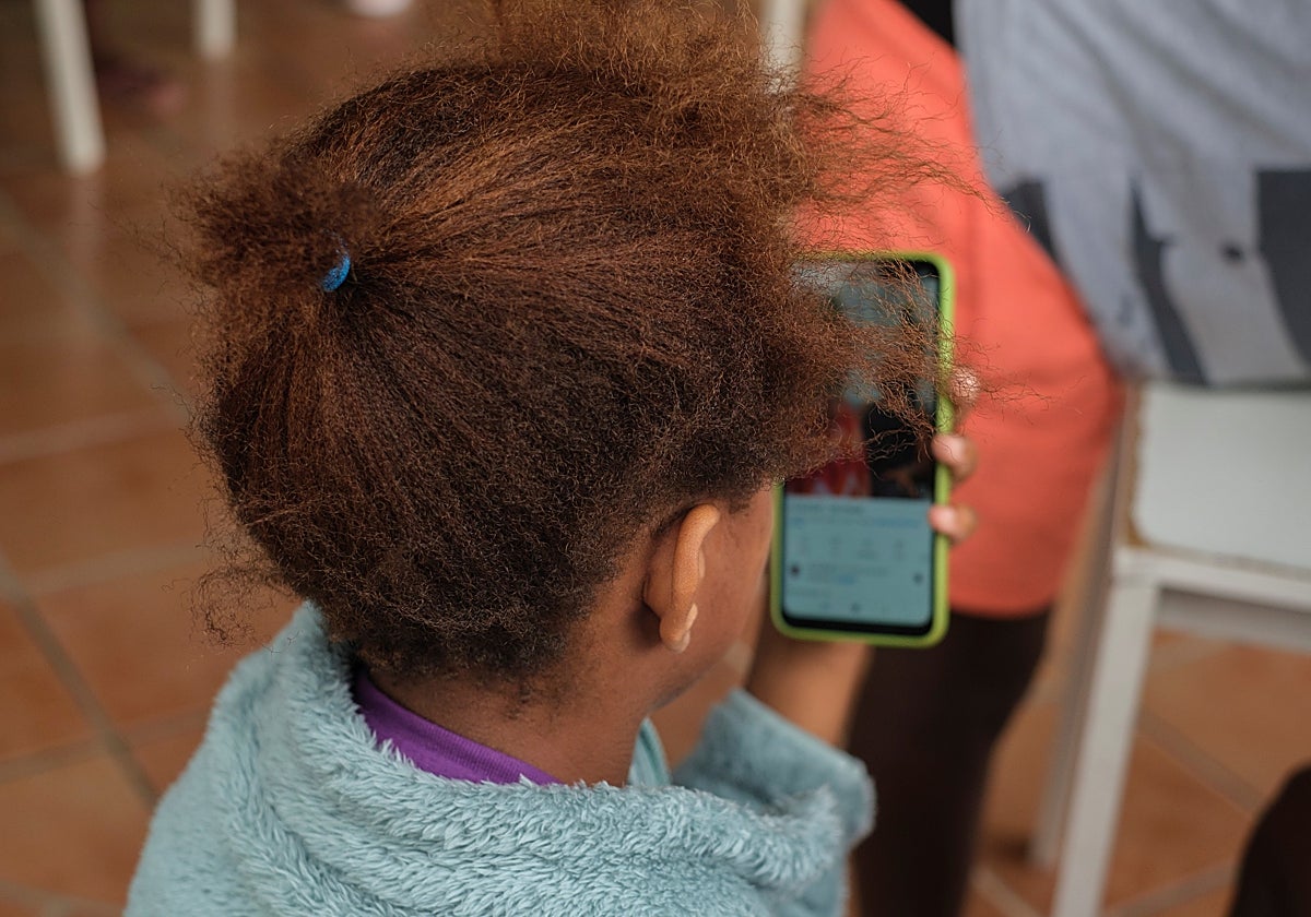 Una escolar utiliza el teléfono móvil