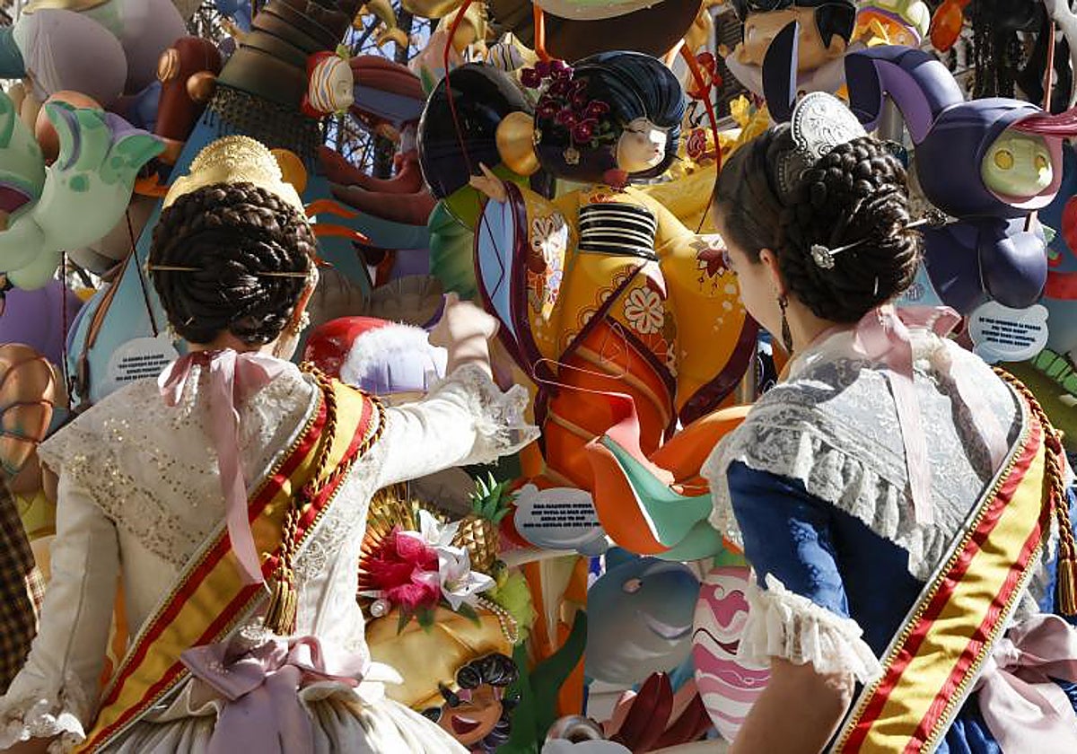 Imagen de dos falleras frente a un monumento en Valencia