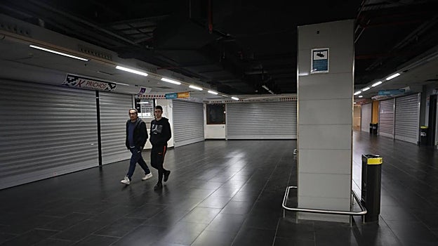 Dos personas caminan entre los locales cerrados del mercado de Torrijos