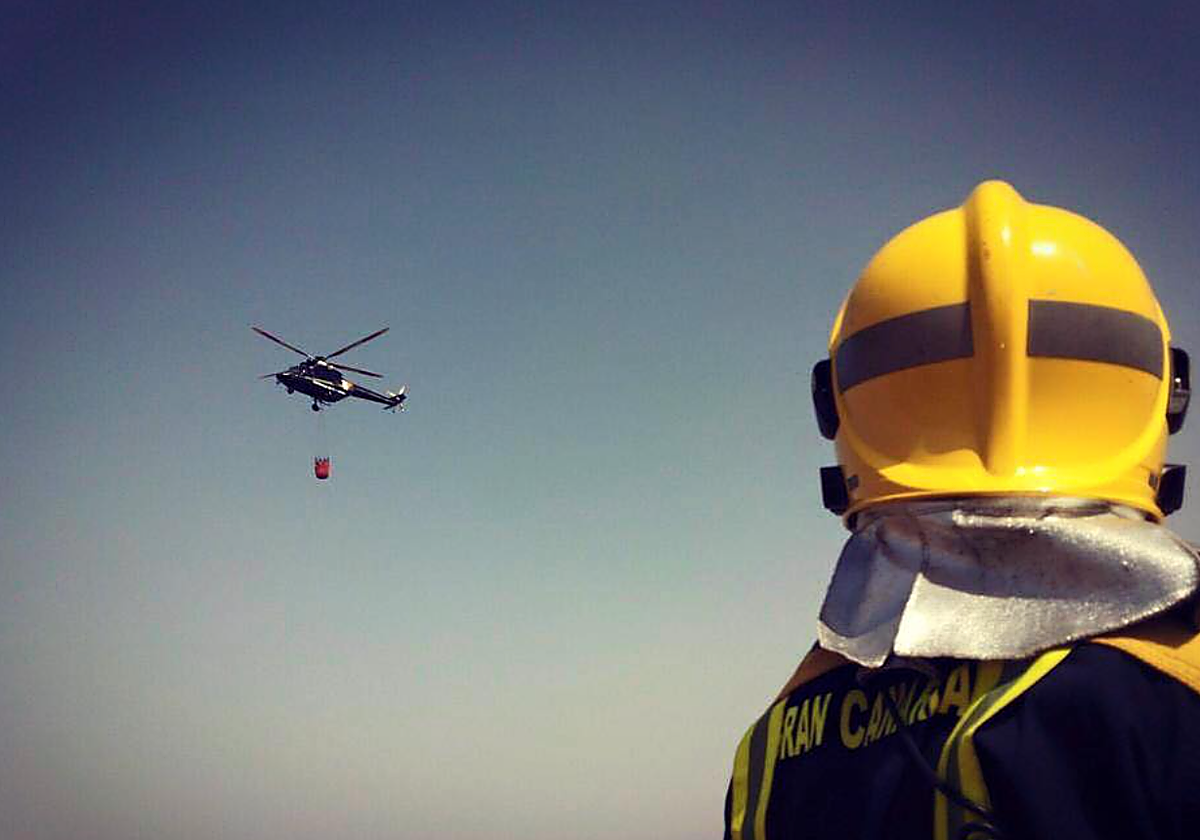 Un helicóptero y un bombero  trabajan en un incendio en foto d archivo