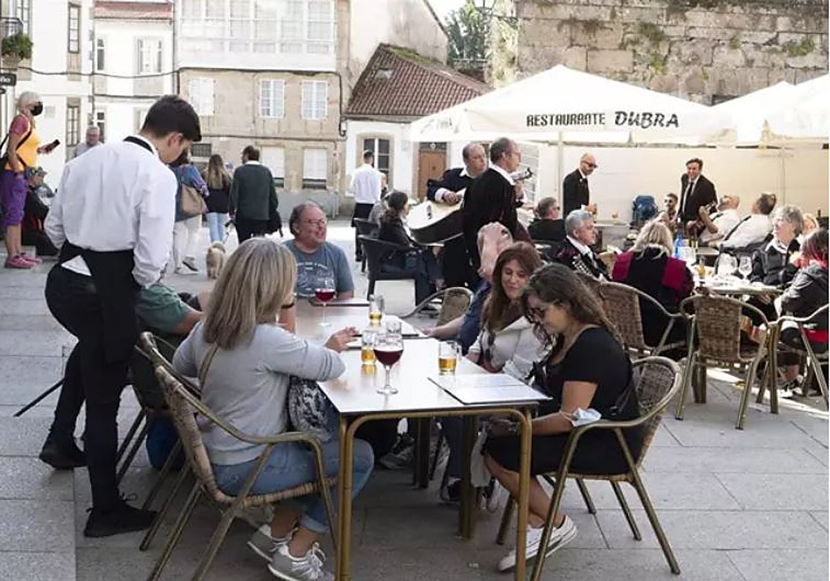 Un grupo de turistas consulta una carta en la terraza de un bar en Santiago de Compostela