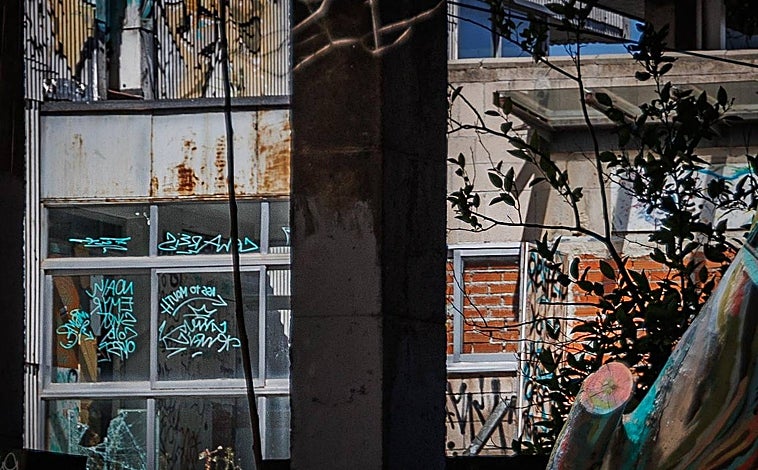 Imagen principal - Ventanas tapiadas con ladrillos y otras con cristales rotos; e interior del colegio mayor (fotos de 2014) con imágenes de los baños y lavadoras en el momento del cierre