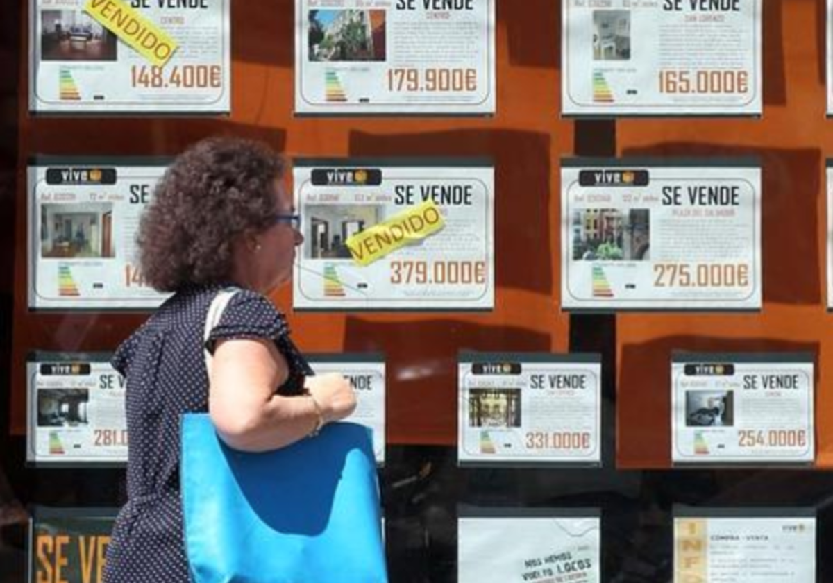 Una mujer pasea frente a una inmobiliaria con pisos en venta, en foto de archivo