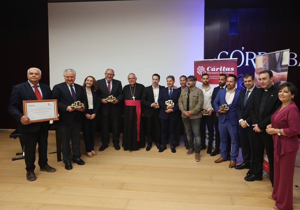 Los premiados, con los directivos de Cáritas y el obispo