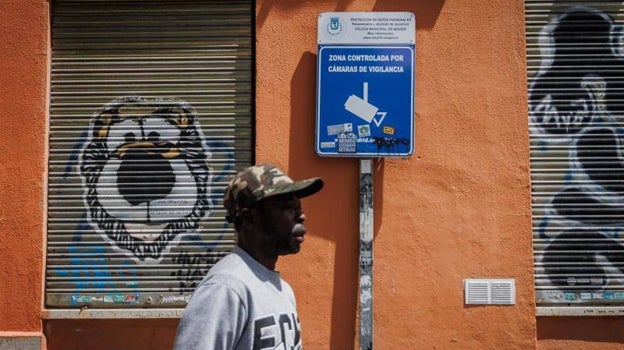 Un vecino de Lavapiés, frente a uno de los carteles que avisa de la videovigilancia en el barrio