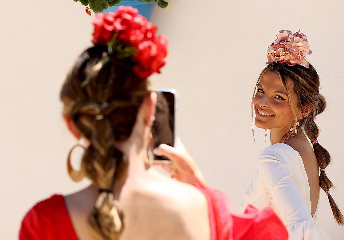 Una joven vestida de flamenca se saca una foto durante la pasada Feria