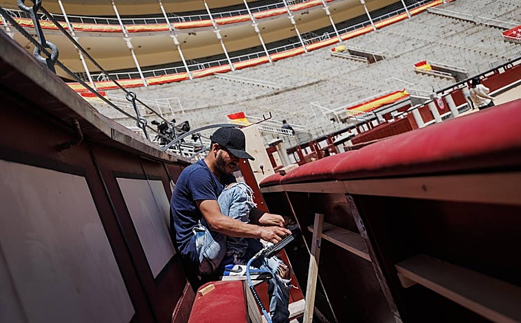 Imagen principal - Un trabajador da los remates en el burladero de Las Ventas, mientras otros limpian e instalan las losetas nuevas en la puerta de arrastre y trabajan en las rejas y arcos del exterior