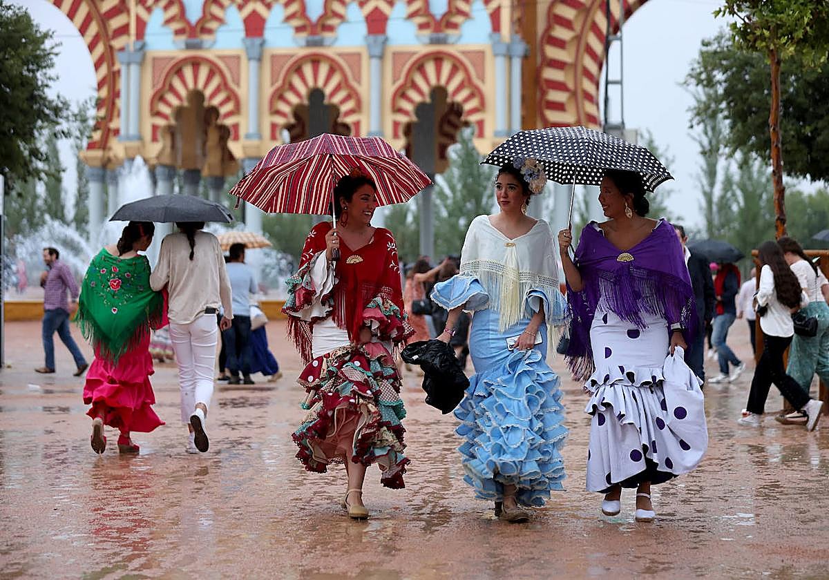 Tres mujeres se protegen de lluvia en la Feria durante la tarde del sábado