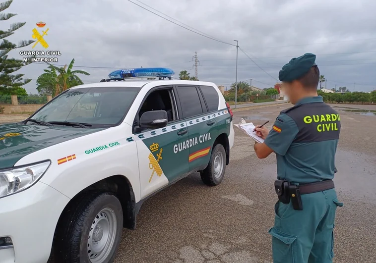 Imagen de archivo de un agente de la Guardia Civil frente a su coche patrulla