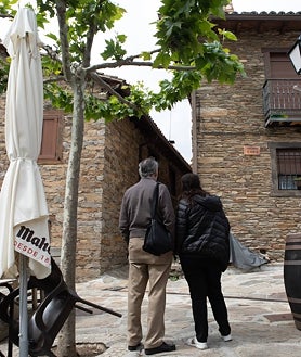 Imagen secundaria 2 - Imagen de la plaza principal de La Hiruela, con la iglesia; Paco, el exalcalde; y un matrimonio paseando por las calles