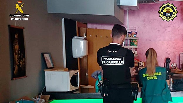 Imagen de un policía local y una miembro de la Guardia Civil realizando las pesquisas en la asociación cannábica
