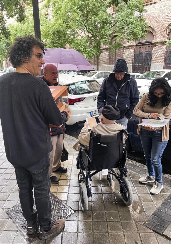 Bajo una llovizna, los miembros de una mesa electoral del instituto Santa Engracia de Madrid han sacado una urna a la calle para facilitar que un anciano en silla de ruedas pudiera votar ante la dificultad de acceder al local por no tener rampa.