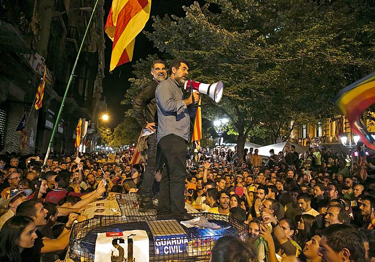 Jordi Sànchez, con un megáfono, y Jordi Cuixart, subidos a un coche de la Guardia Civil, a las puertas de la Consejería de Economía, el 20 de septiembre de 2017