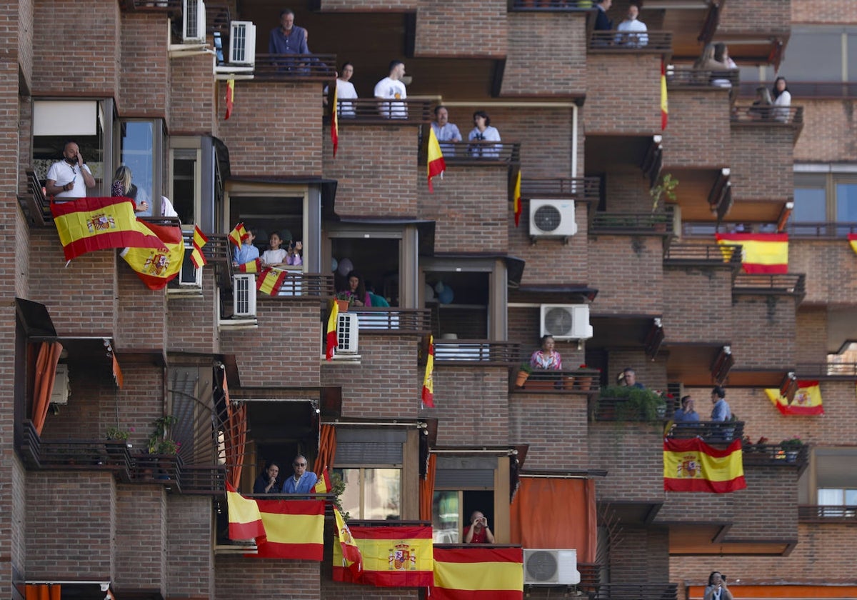 Vecinos de Granada esperan desde sus balcones, engalanados con banderas de España, a que comience el desfile del Día de las Fuerzas Armadas