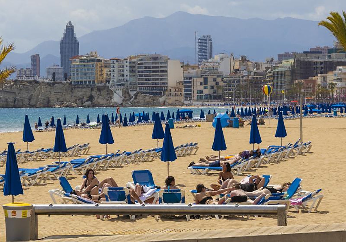 Turistas en tumbonas en la playa en Benidorm