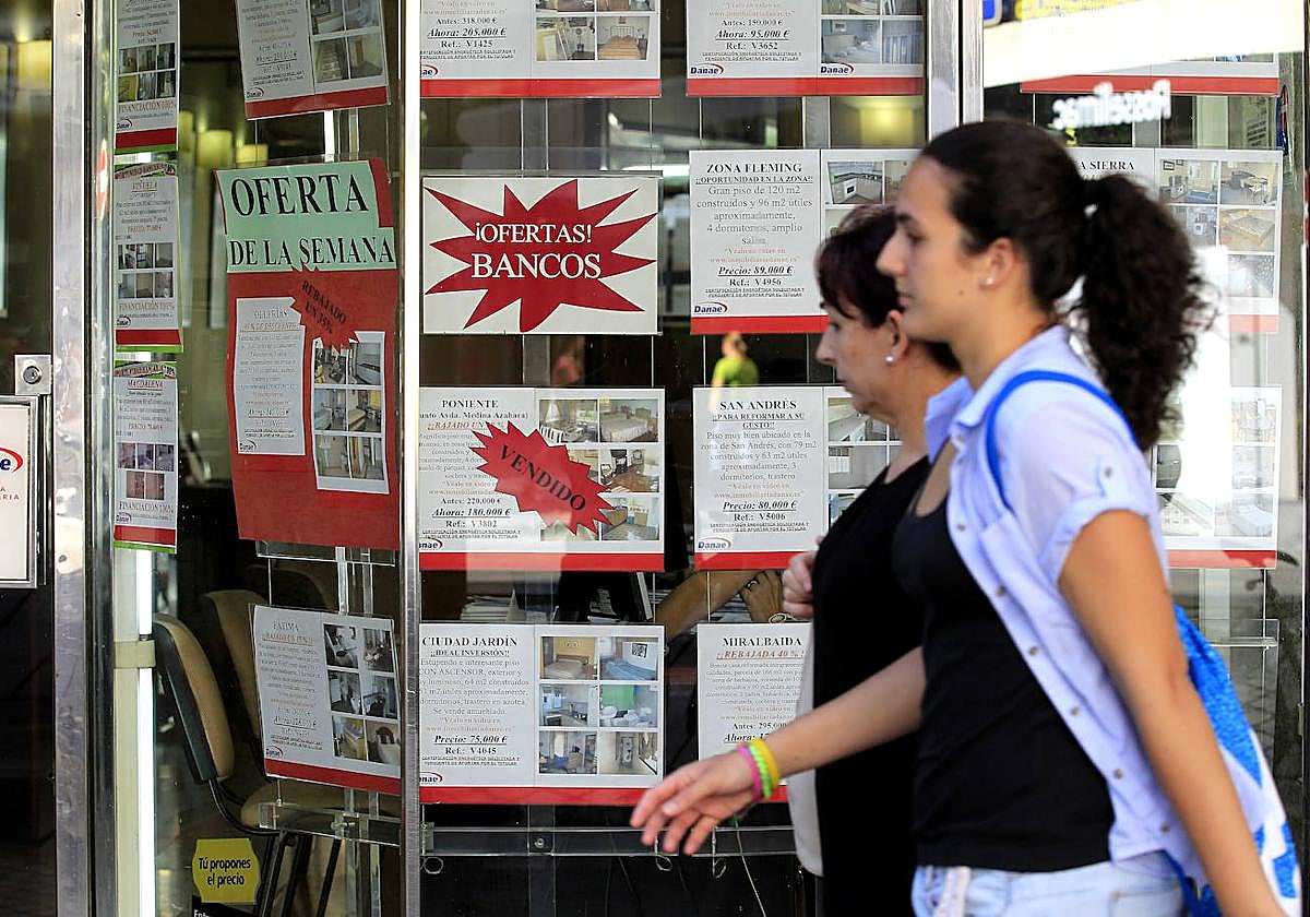Dos mujeres pasan delante del escaparate de una inmobilliaria
