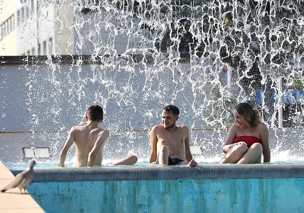 Unos jóvenes se refrescan durante esta ola de calor en una de las fuentes del Vial Norte