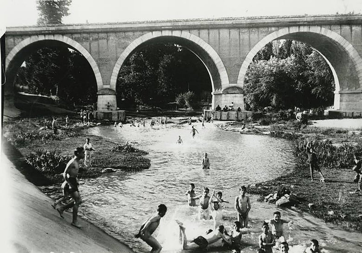 Varias personas, entre ellas niños, se bañan en las aguas del Manzanares bajo el Puente de los Franceses, en 1918
