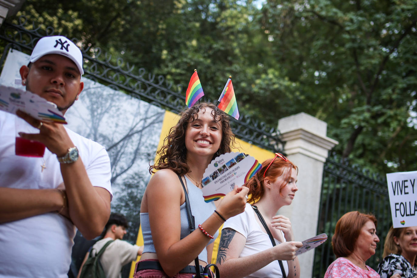 Una chica que participa en la marcha llevando dos banderas del arcoíris en la cabeza