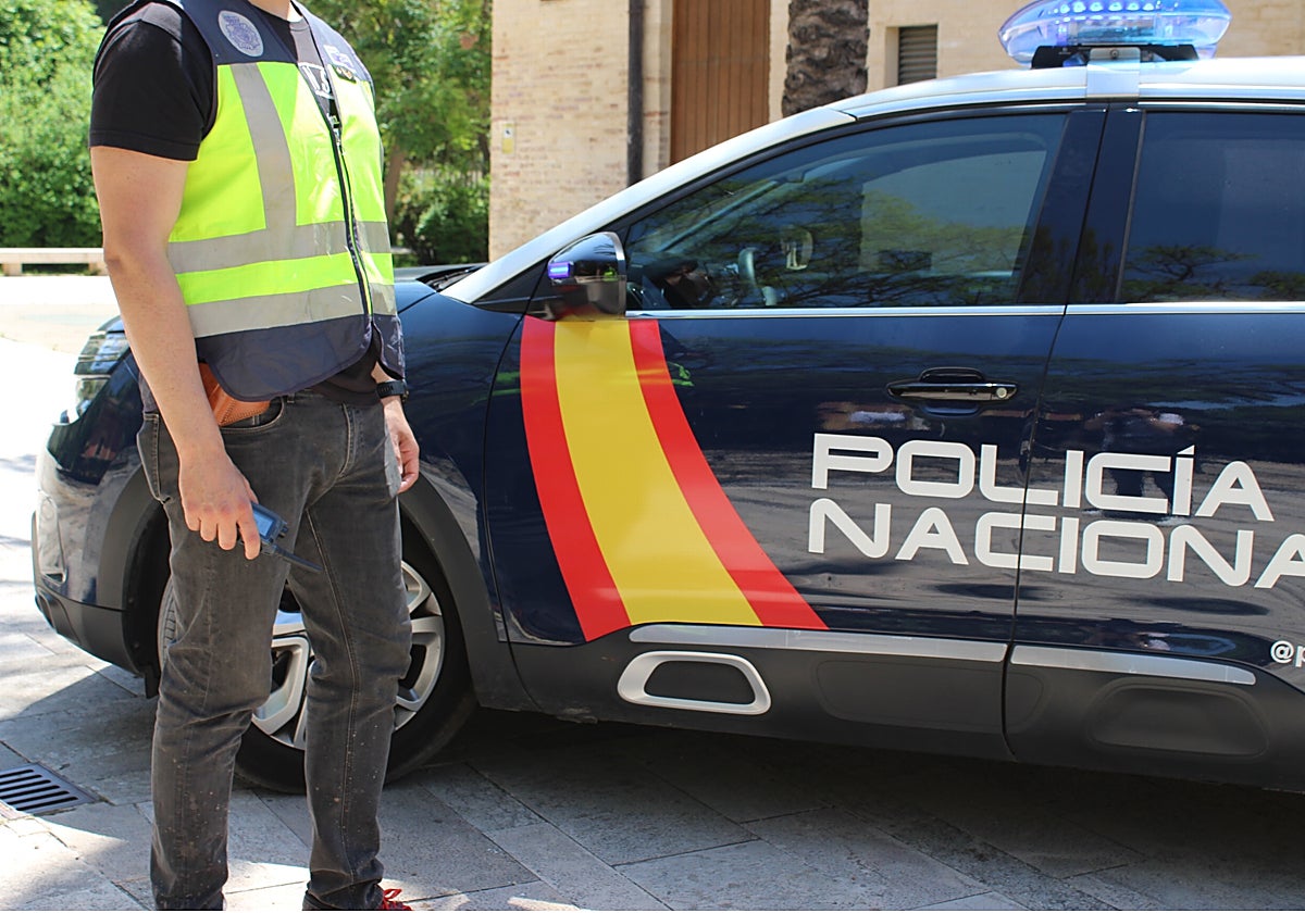 Un agente de la Policía Nacional junto a un coche patrulla